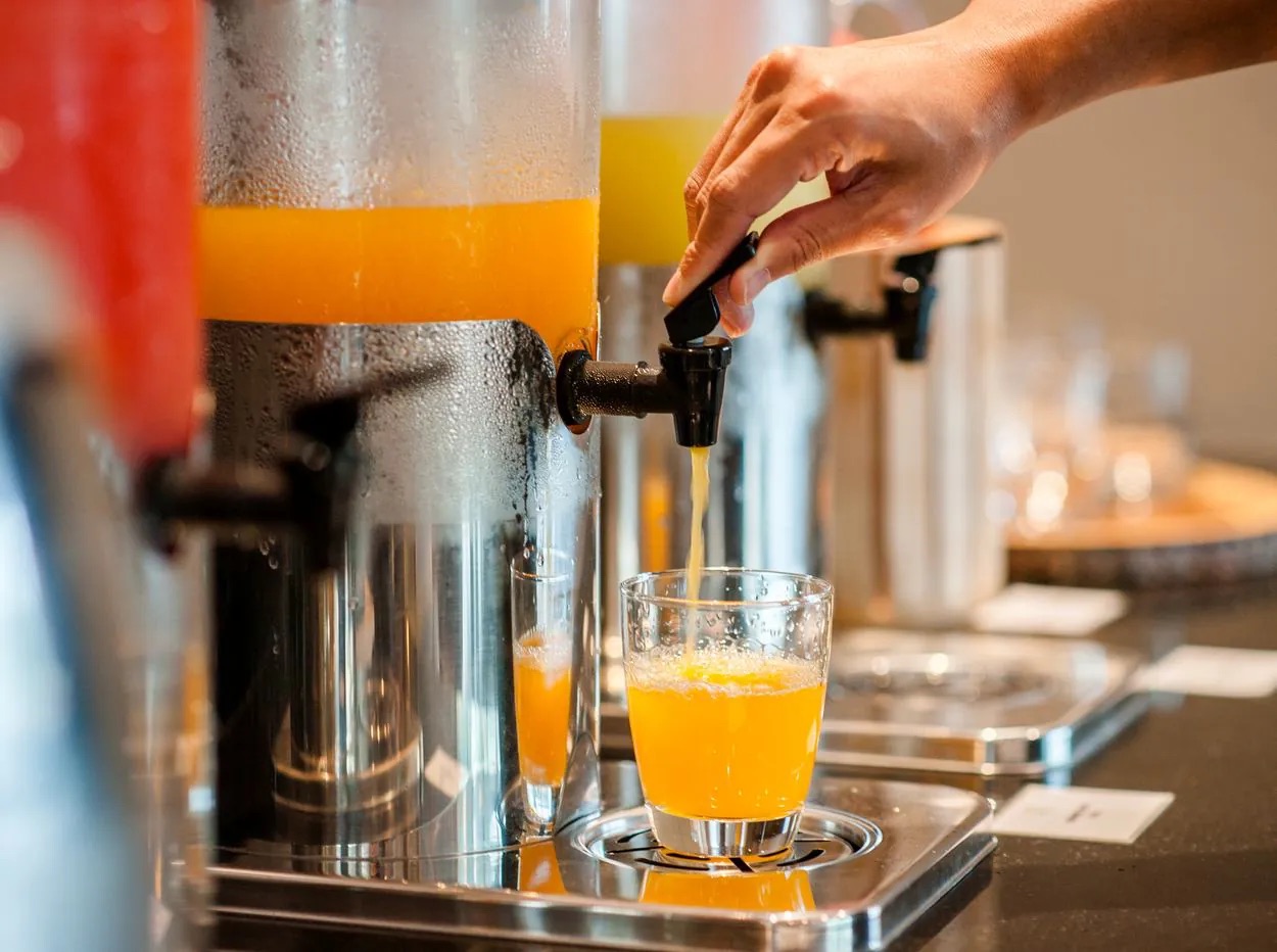 Jugo de naranja servido desde el dispensador en el desayuno de un hotel